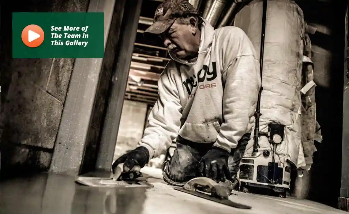 Foreman using a trowel to apply waterproofing material to a basement wall.
